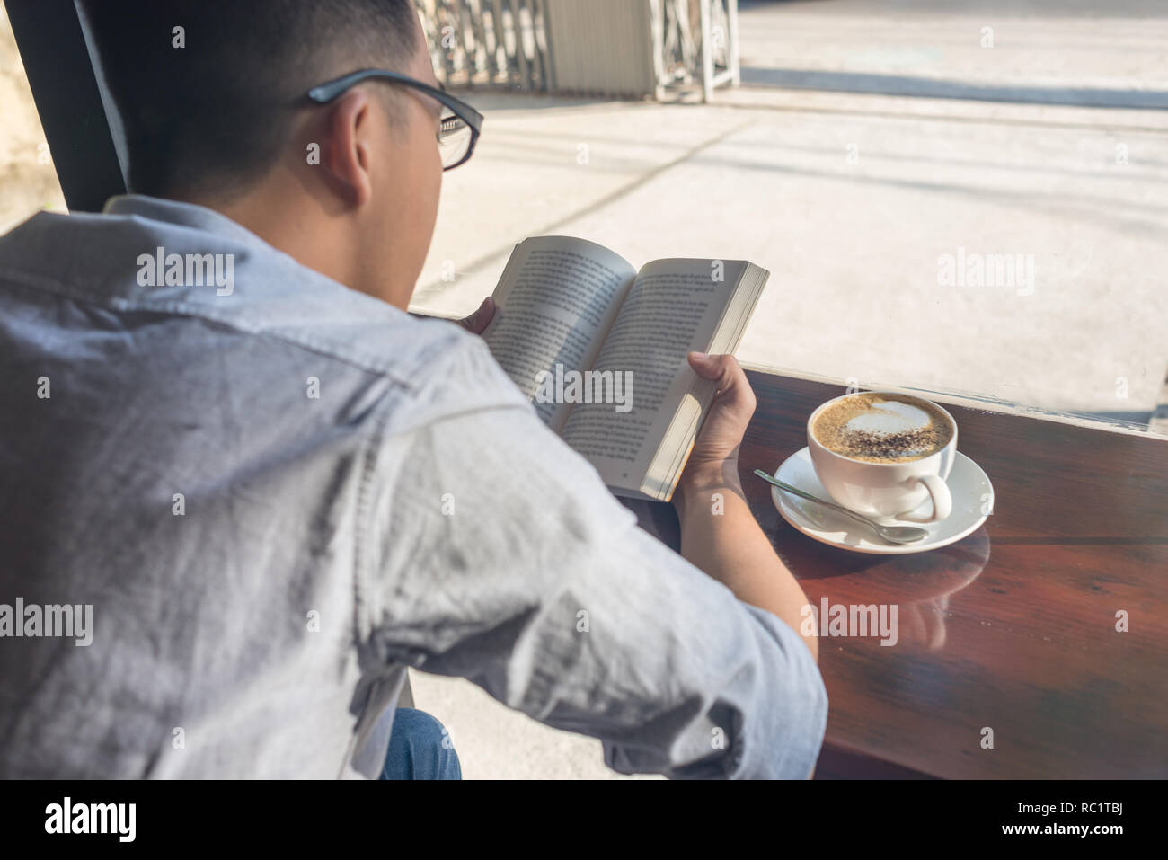 Young man reading book and drinking coffee Stock Photo