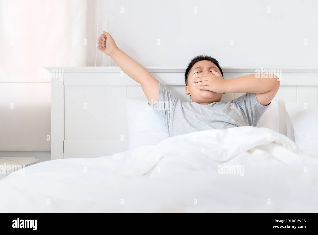 Obese fat boy wake up yawning and stretch on bed in morning. lazy