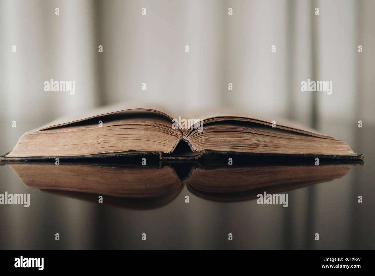 Opened old book with reflected in brown surface Stock Photo