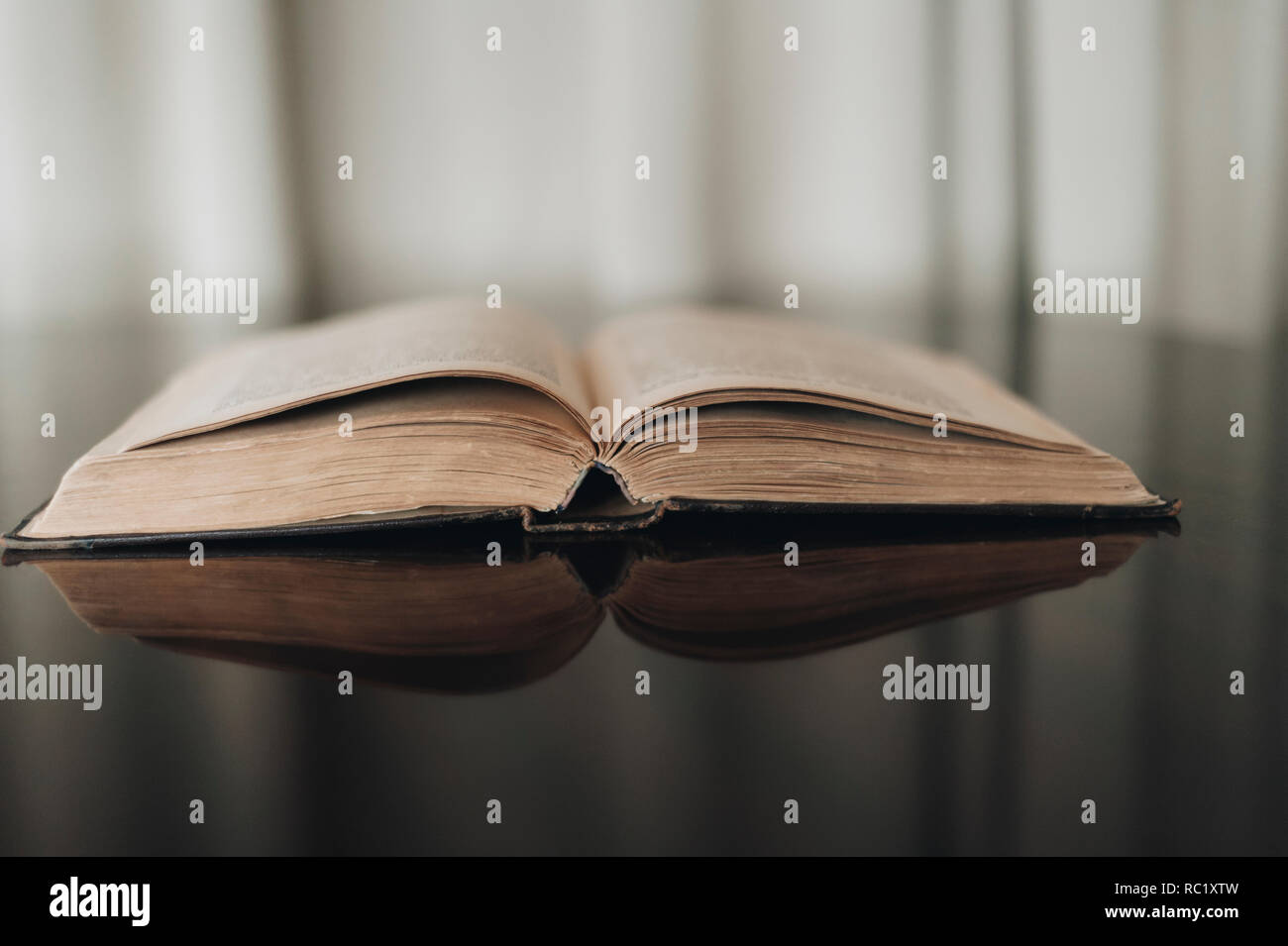 Opened old book with reflected in brown surface Stock Photo