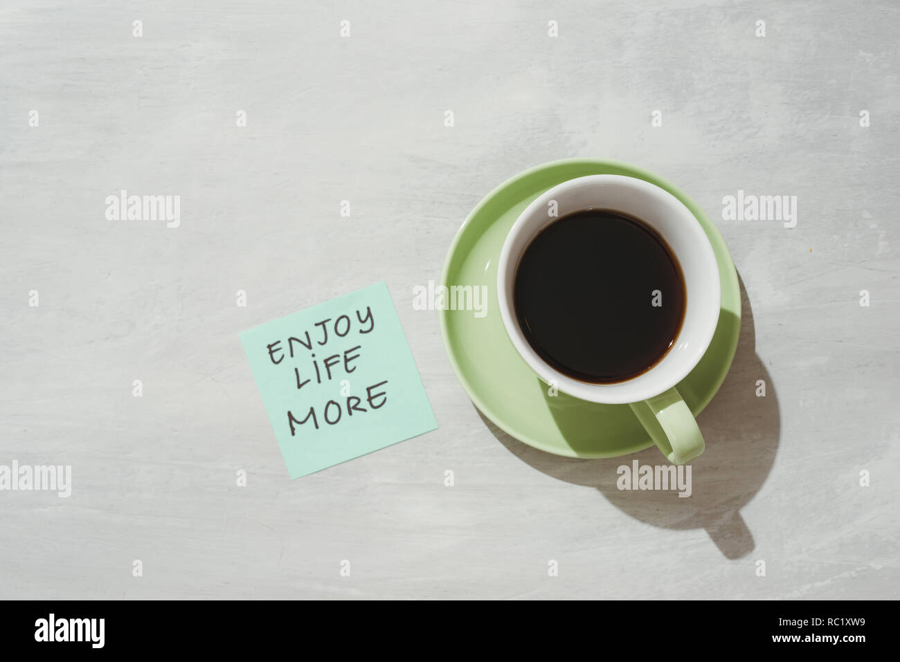 Paper note stick on green coffee mug with text - Enjoy life more Stock Photo