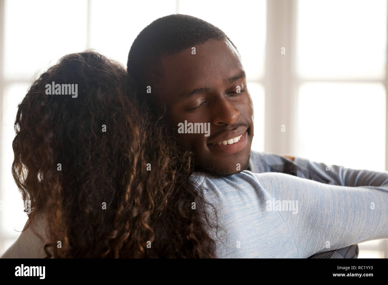 Happy affectionate black husband embracing wife enjoying sincere Stock Photo