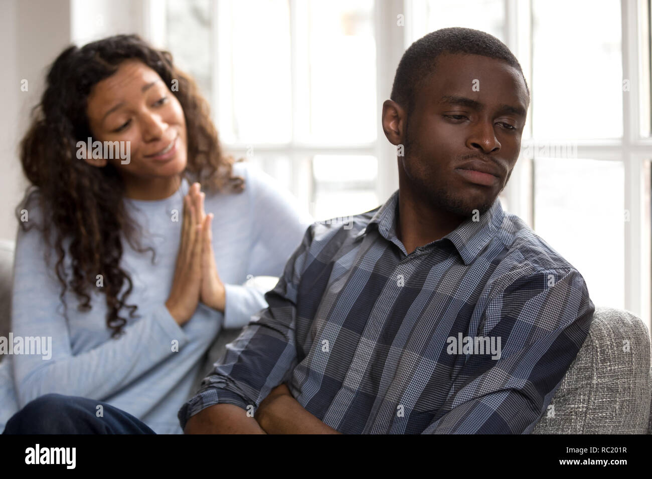 Guilty african woman apologizing asking black husband for forgiv Stock Photo