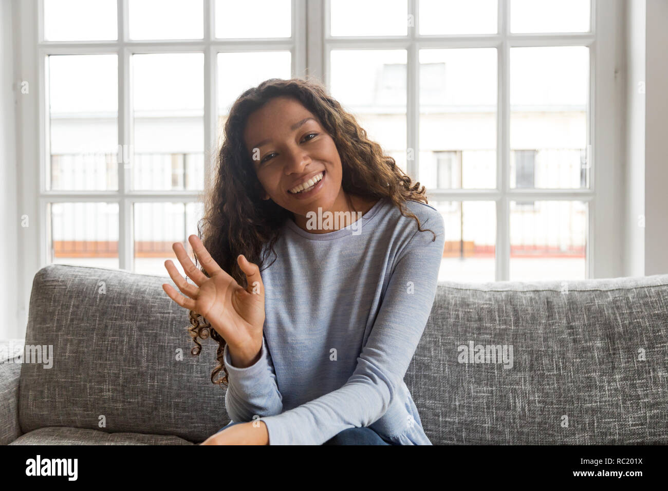 Happy friendly african american woman waving hand looking at cam Stock Photo
