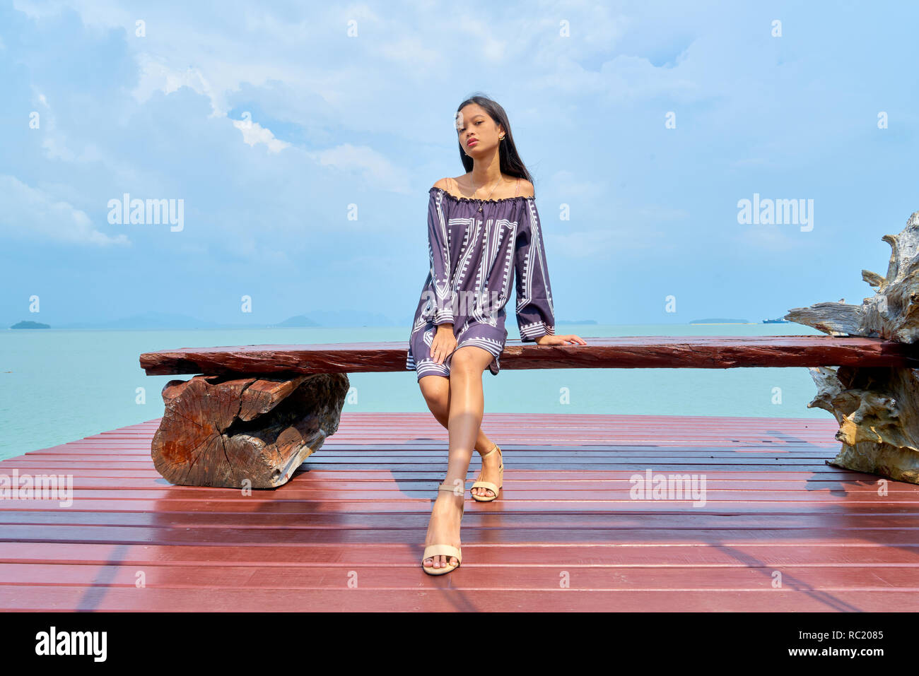 Beautiful woman posing - sitting on bench, looking at camera and pensive Stock Photo