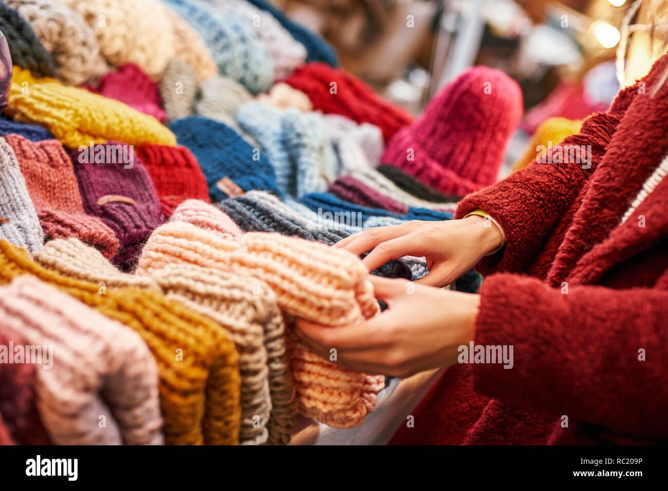 Wide choise of caps. Close-up of happy young joyful woman choosing caps at small street market. Autumn season, blond haired woman with her boyfriend a Stock Photo