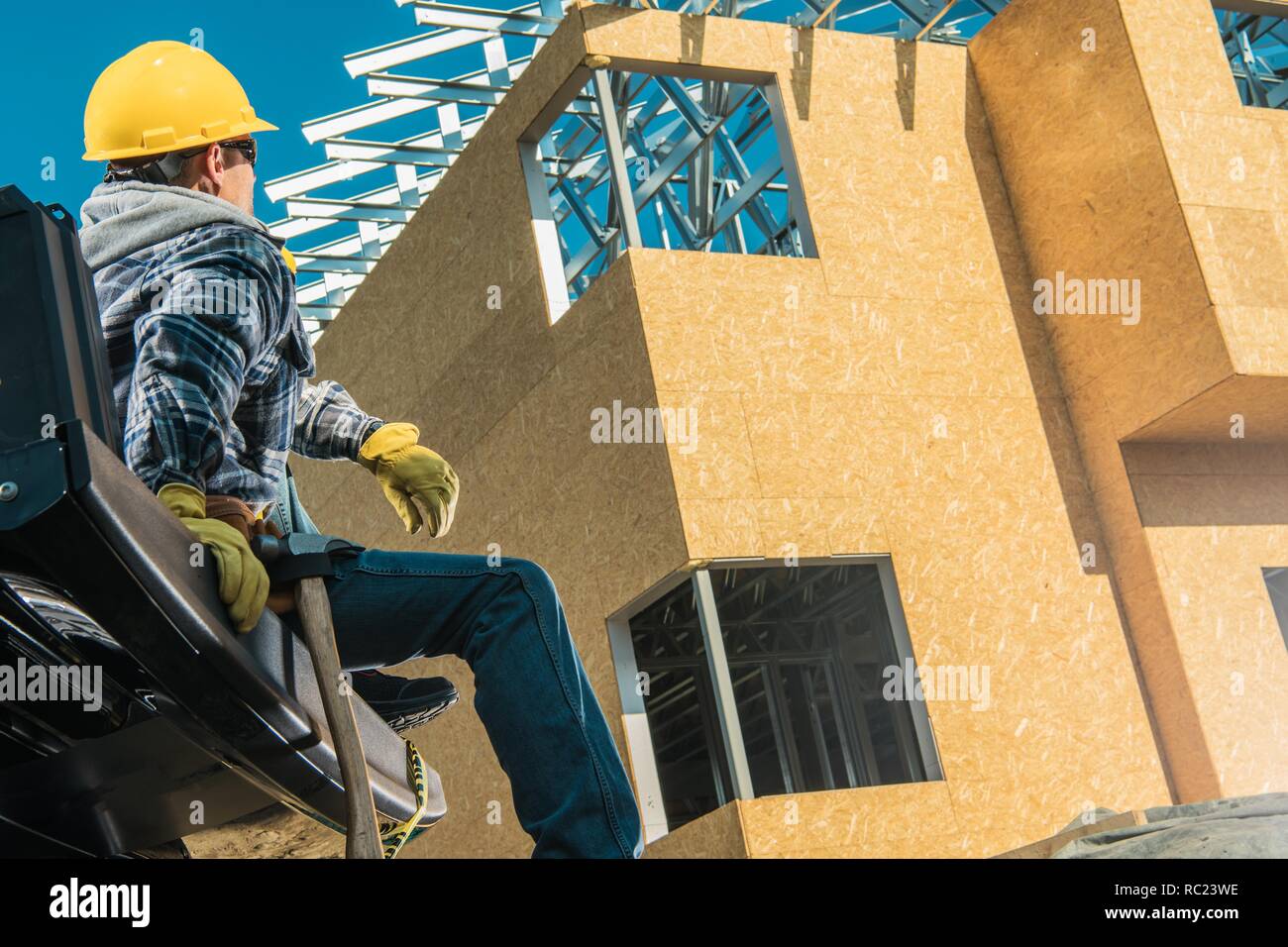 Caucasian House Builder. Construction Worker in His 30s Wearing Yellow Hard Hat Taking Look at the Skeleton Steel While Taking Break. Stock Photo