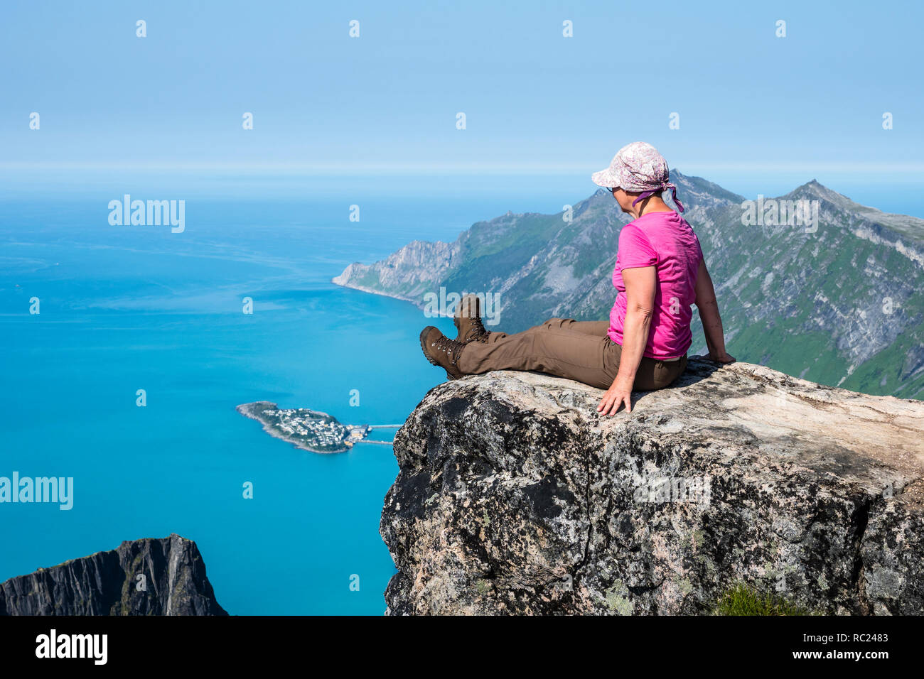 Woman looks over fjord Örnfjord towards island Husöy, top of mountain Grytetippen, island Senja, Troms, Norway Stock Photo