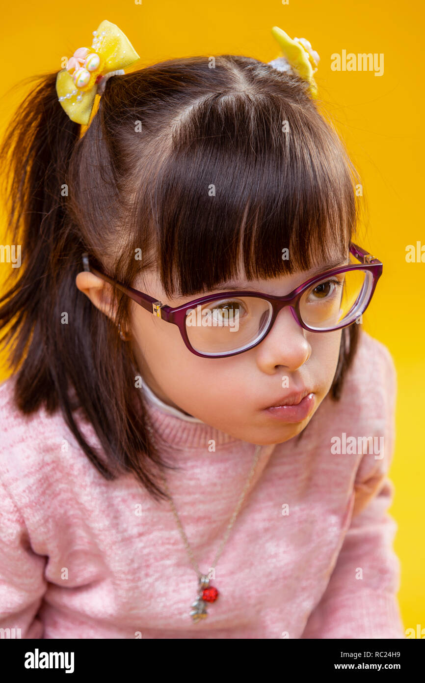 Resolute little dark-haired lady wearing pretty necklace on pink sweater Stock Photo