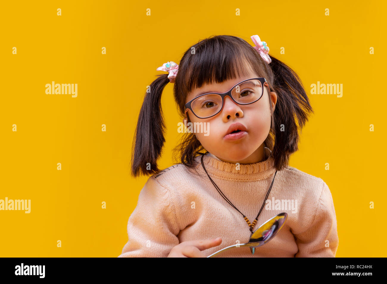 Curious small funky girl holding big metal spoon Stock Photo