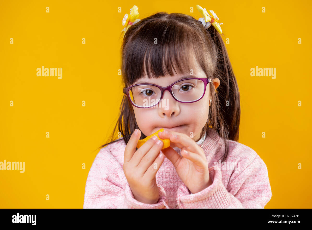 Short-haired unusual child with big brown eyes eating unhealthy snacks Stock Photo