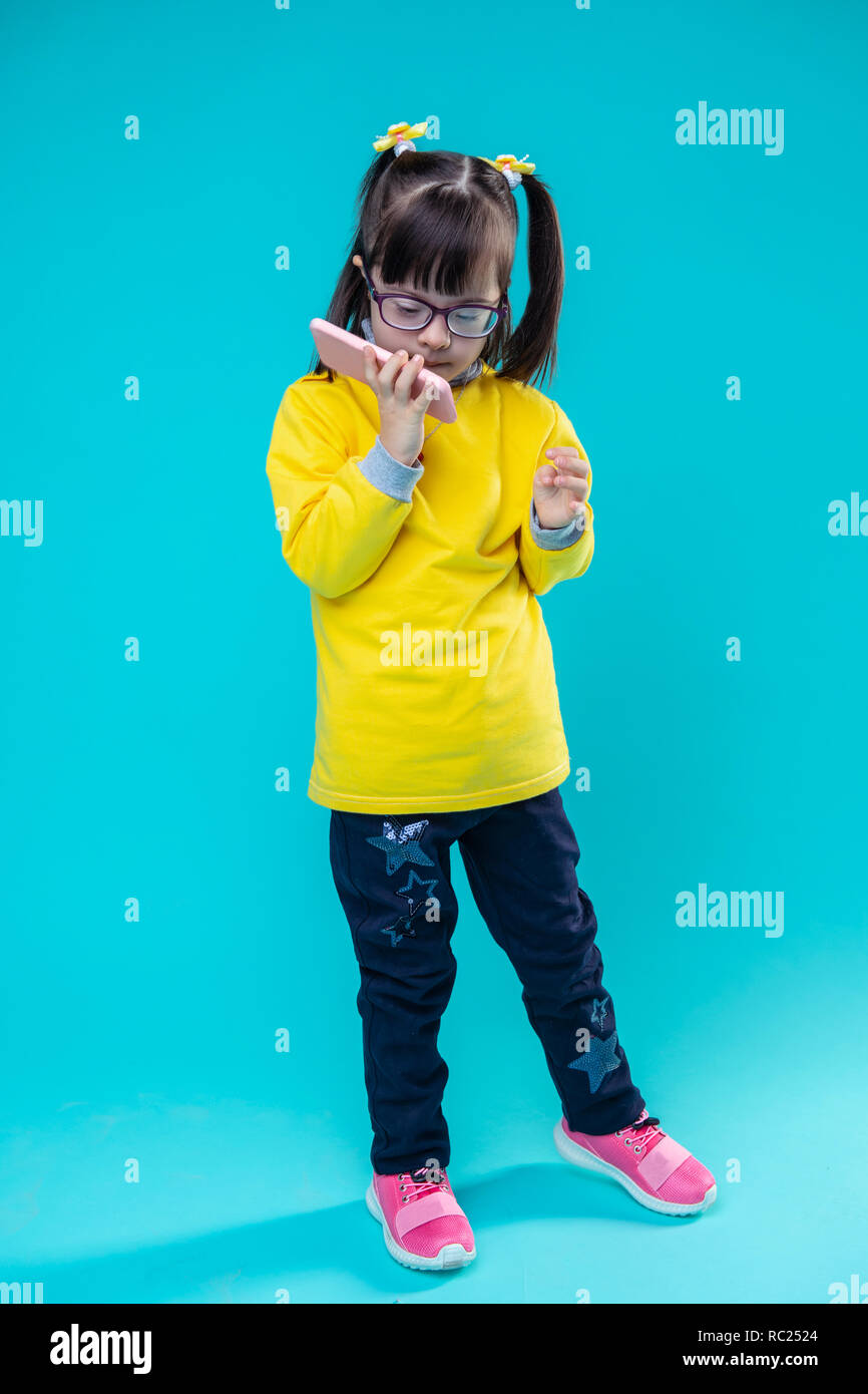 Curious little lady with down syndrome attaching her smartphone Stock Photo