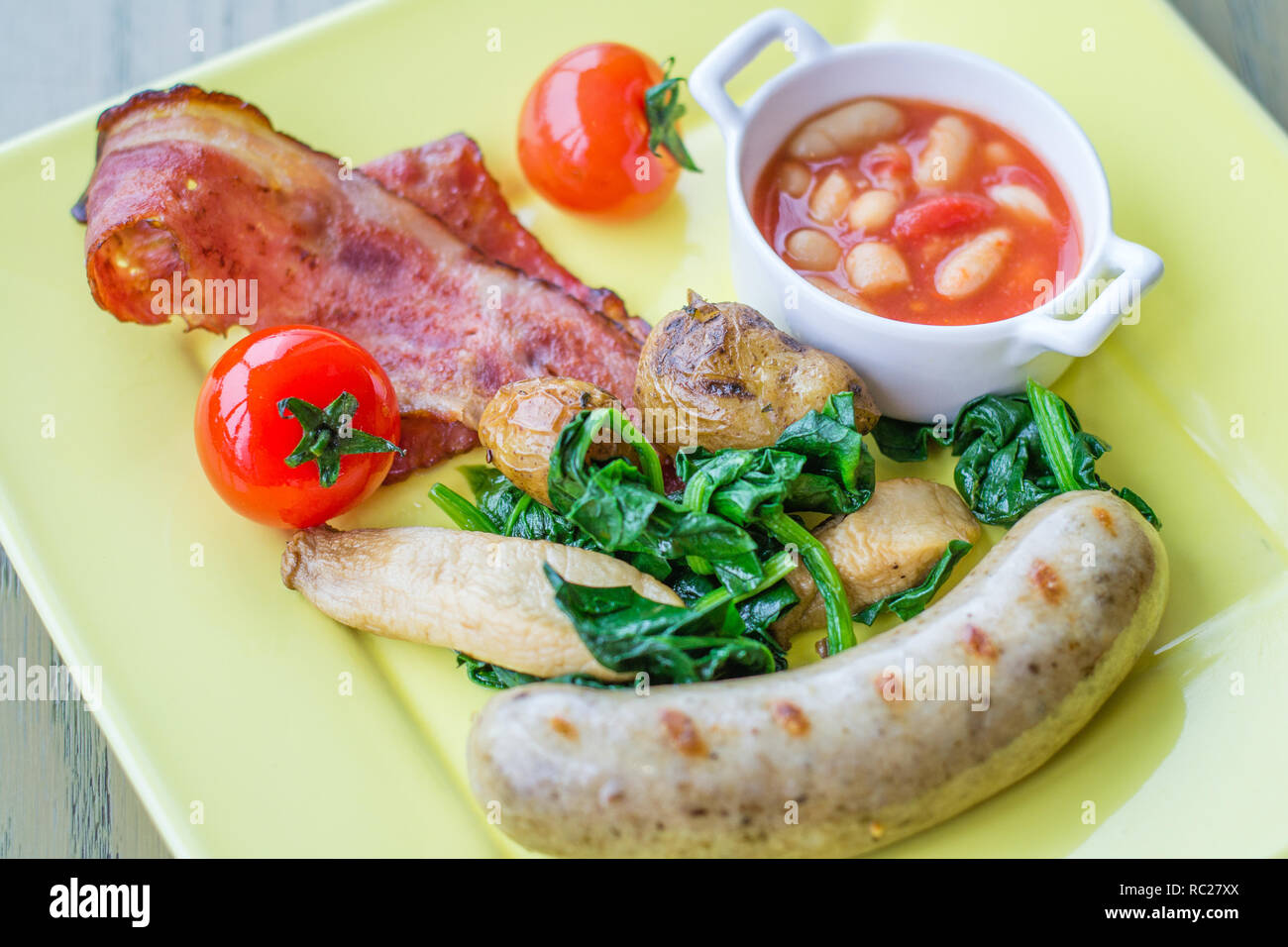 sausage bratwurst with bacon, baked beans, spinach, tomato Stock Photo