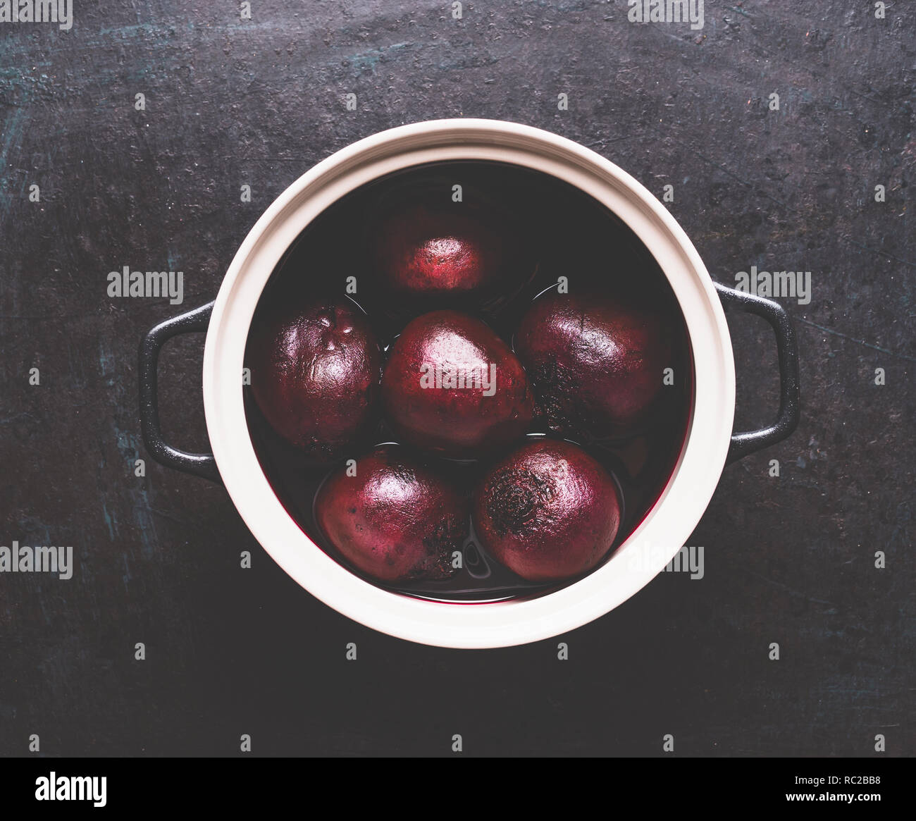 Whole boiled beets in cooking pot on dark background, top view. Healthy