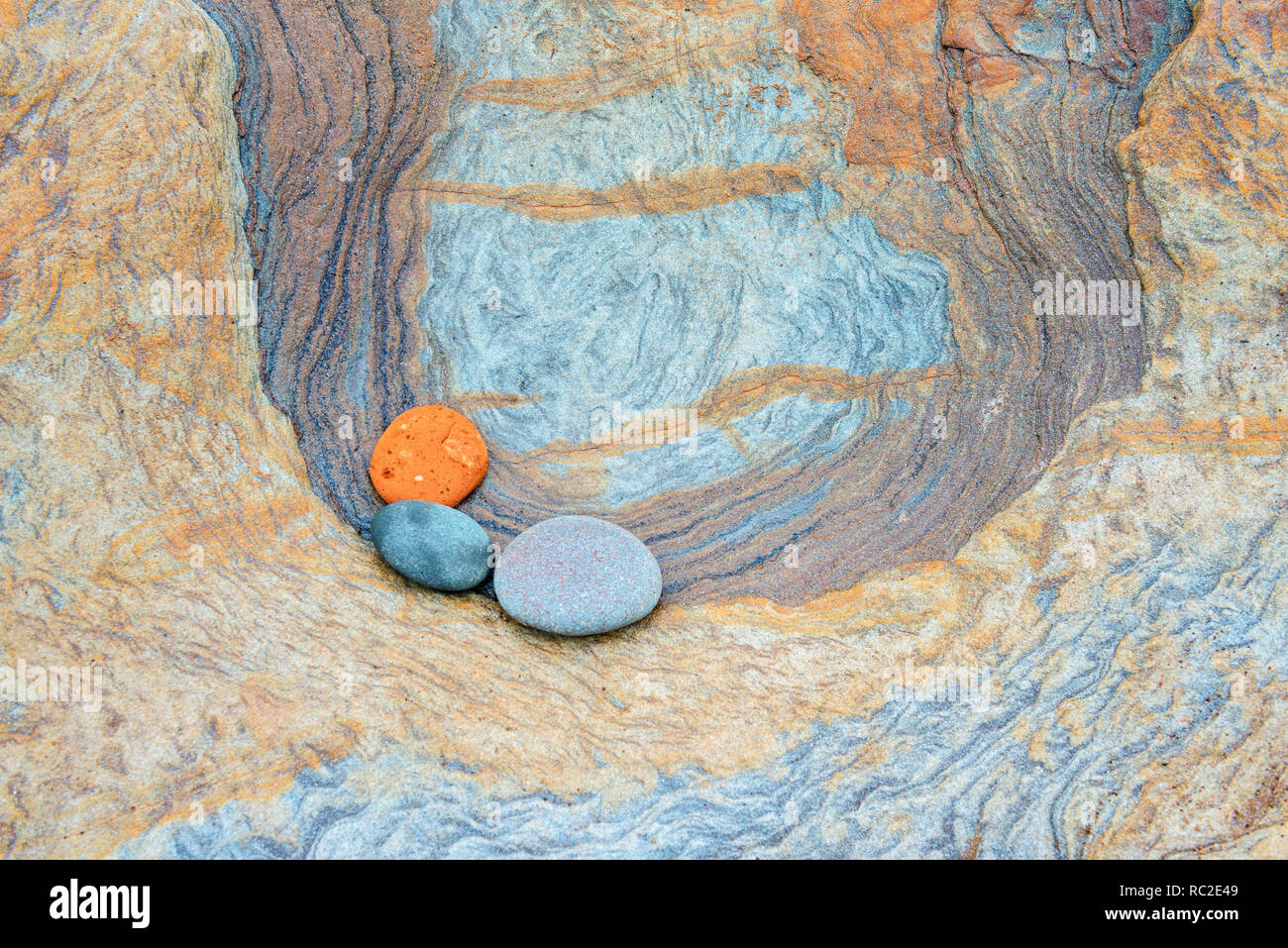 Colourful patterns created by sea erosion of rocks revealed at low tide on Spittal Beach. one say that the colours are caused by iron ore deposits. Stock Photo