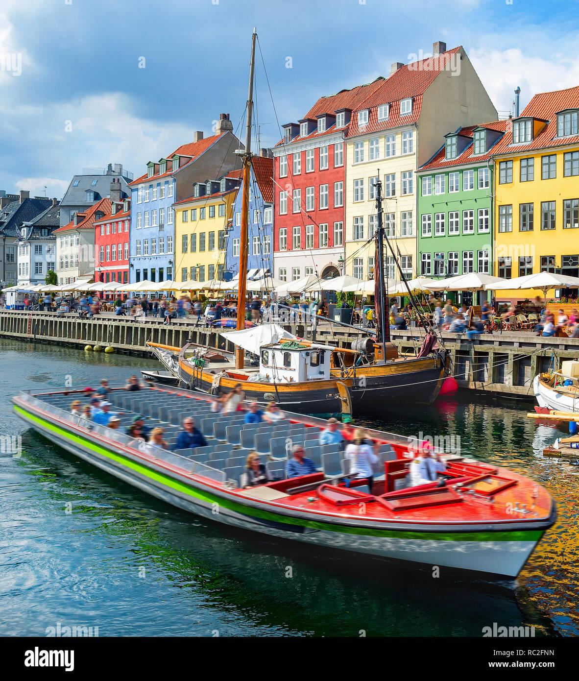 Tourists sightseeing cruising on boat by Nyhavn embankment with bars and restaurants in buildings of old architecture, Copenhagen, Denmark Stock Photo