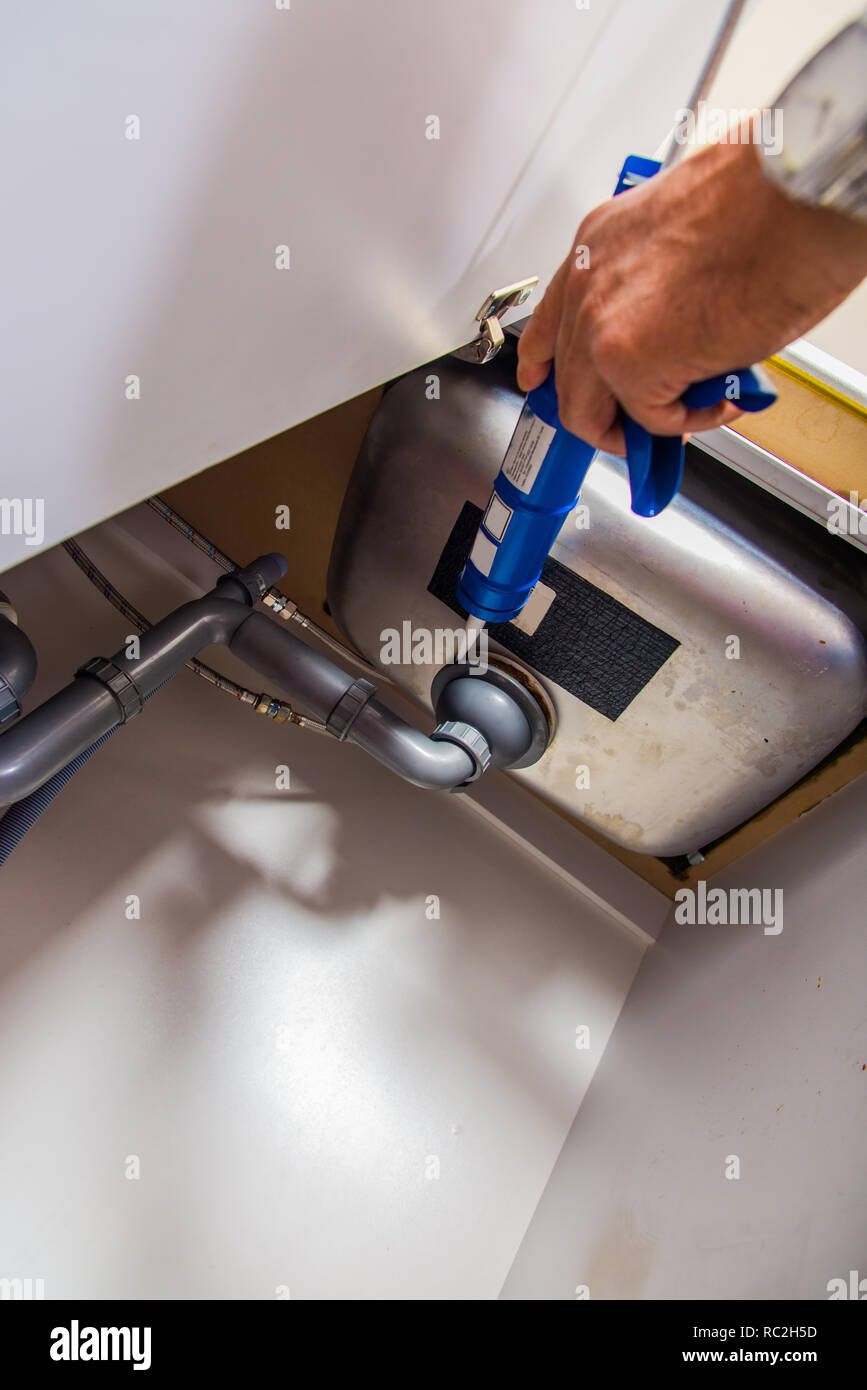 Repairman is fixing the kitchen sink with caulking gun Stock Photo Alamy