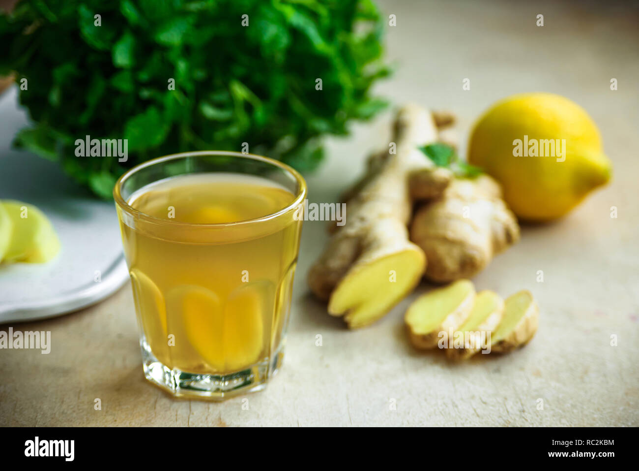Glass with ginger detox water and ingredients near it. Wooden background. Stock Photo
