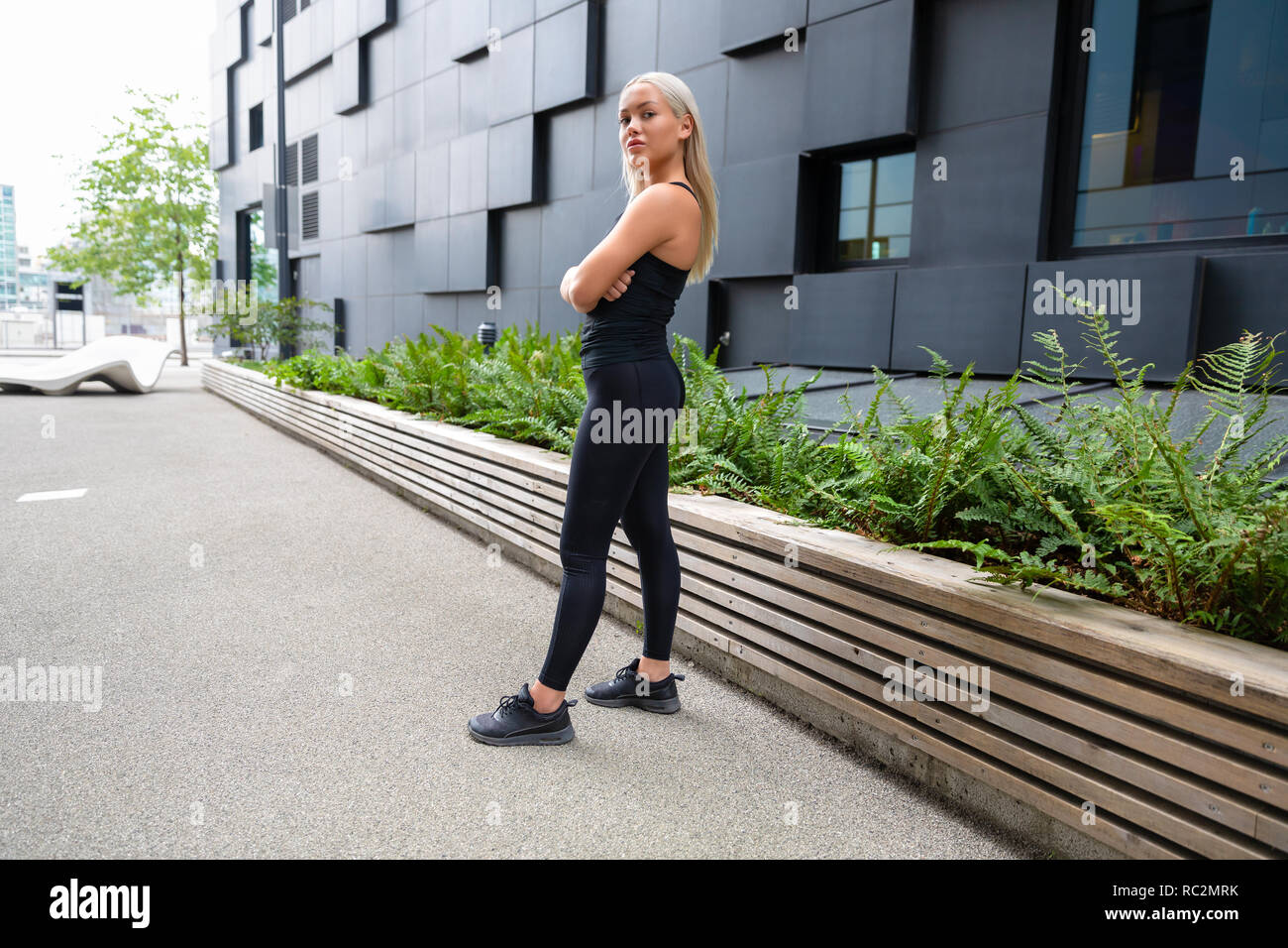 Confident Female Urban Runner Standing With Her Arms Crossed Stock Photo