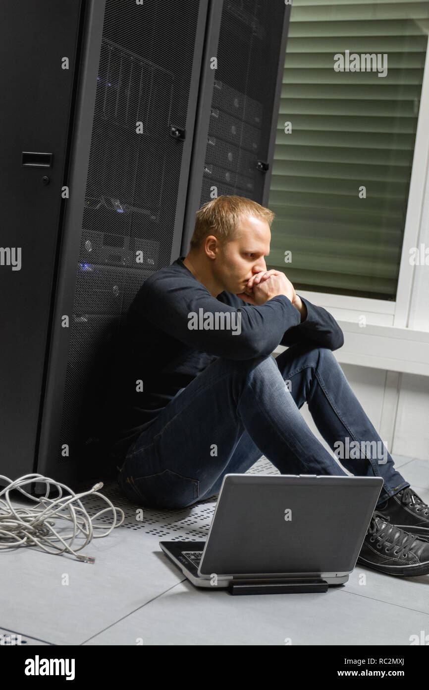 Exhausted Mid Adult IT Consultant Against Servers At Datacenter Stock Photo