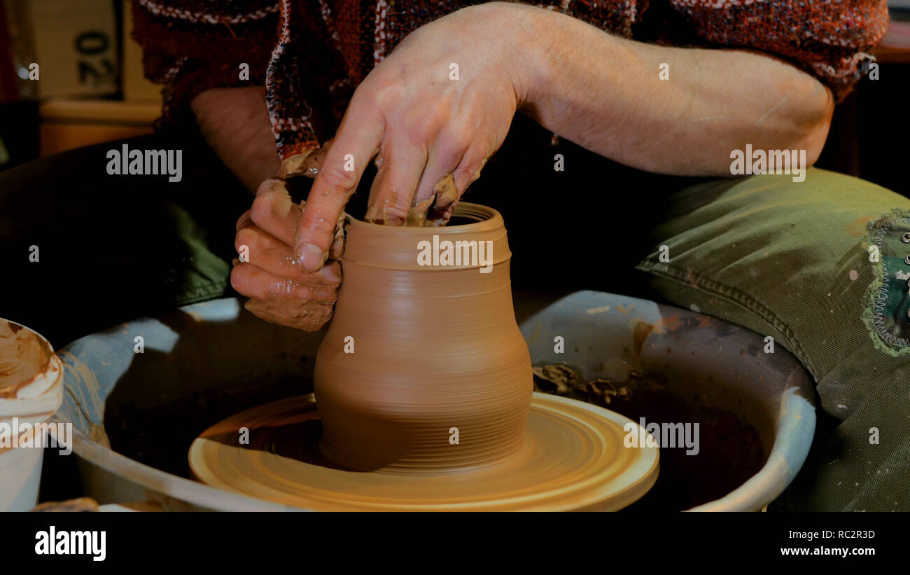 Professional male potter working with clay on potter's wheel in