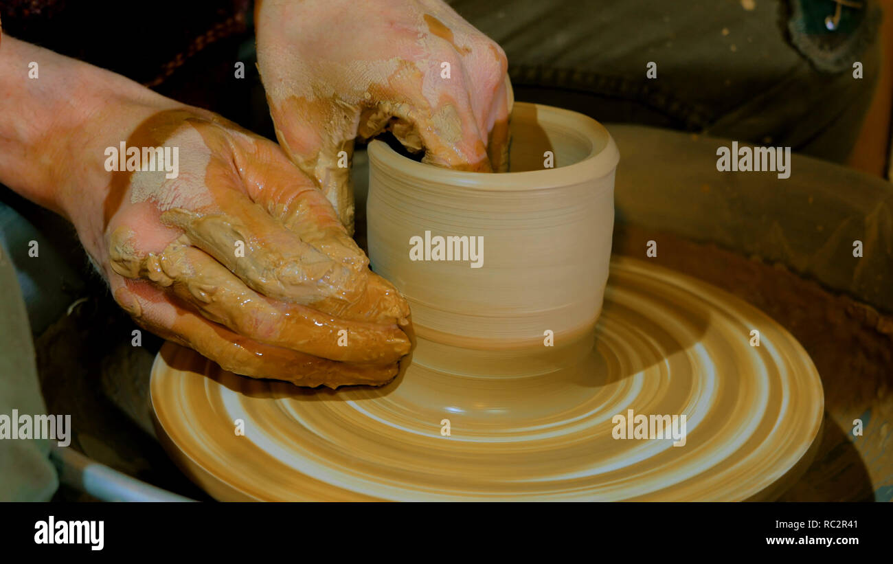 Professional male potter making mug in pottery workshop, studio. Handmade, art and handicraft concept Stock Photo