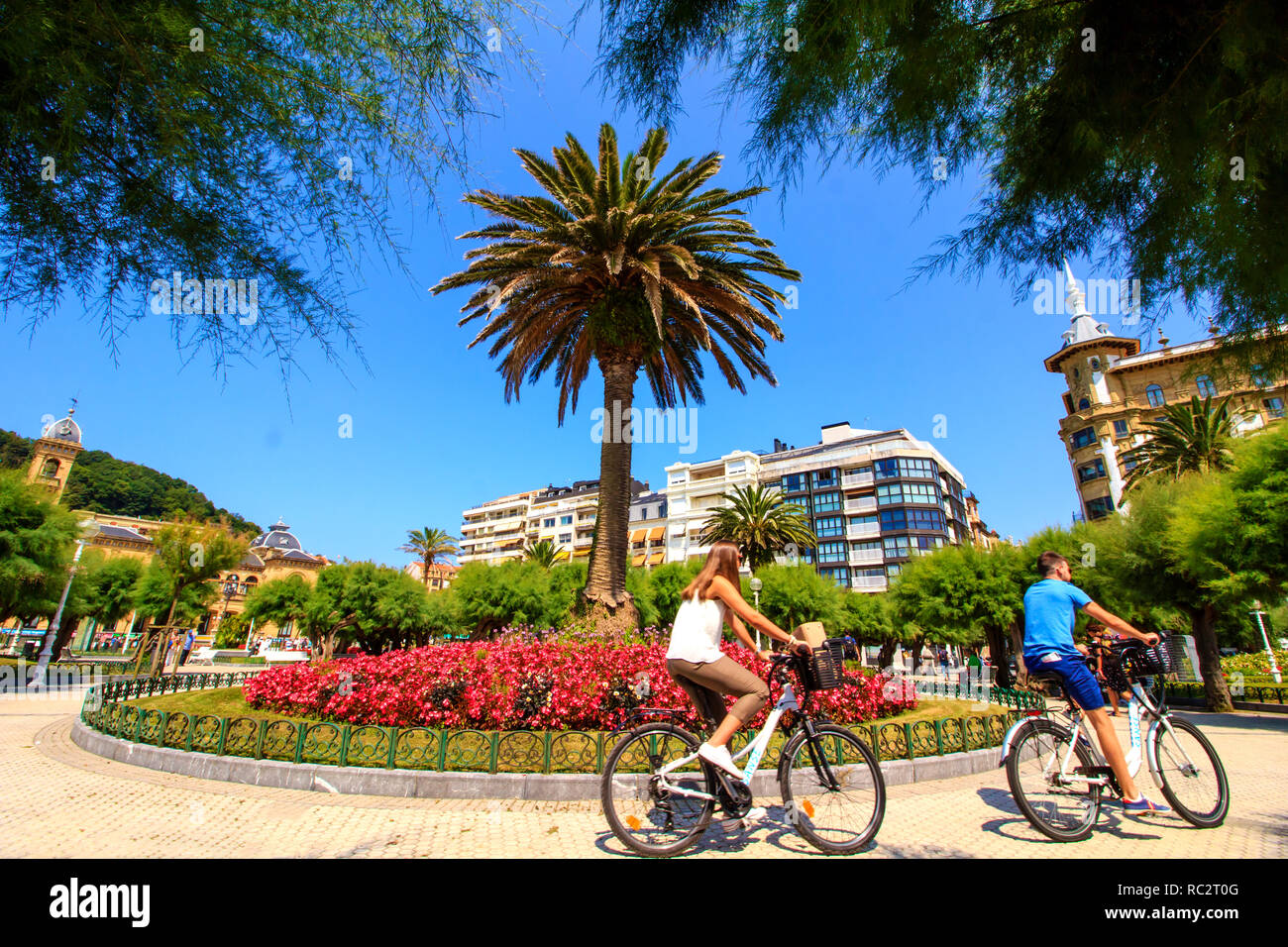 Young couple cycling in the town center of San Sebastian, Spain by beautiful day in August. Stock Photo