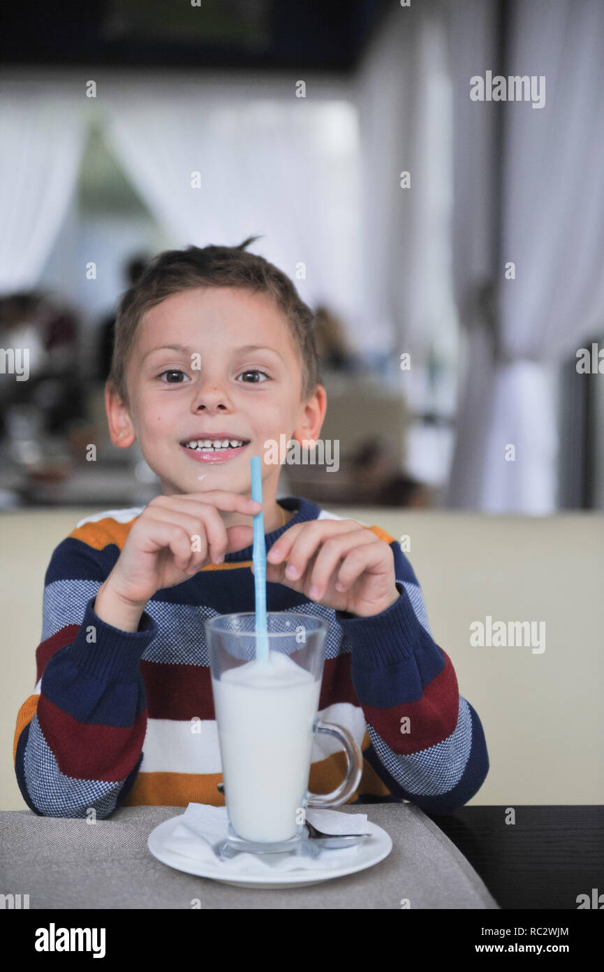 Boy drinking milk through silly straw glasses, while looking up Stock Photo