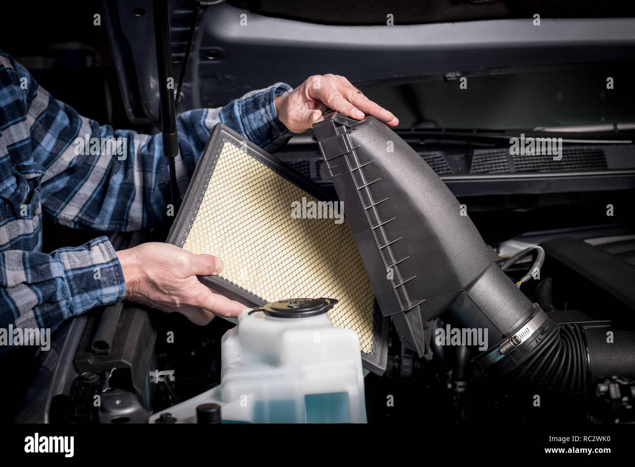 Man lifts the cover for an air filter cavity in a puck up engine