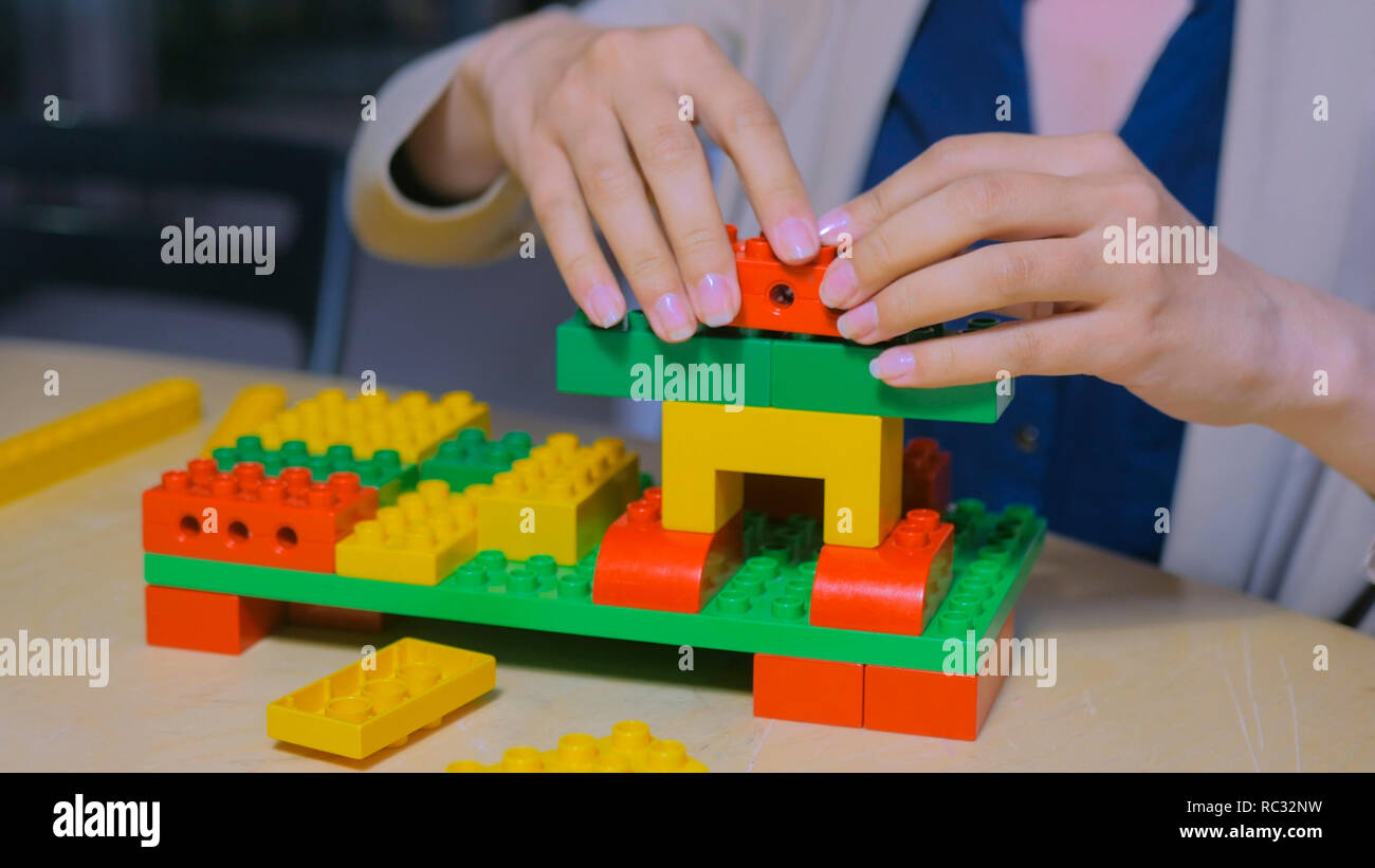 Close up shot of woman hands playing with colorful plastic blocks constructor Stock Photo