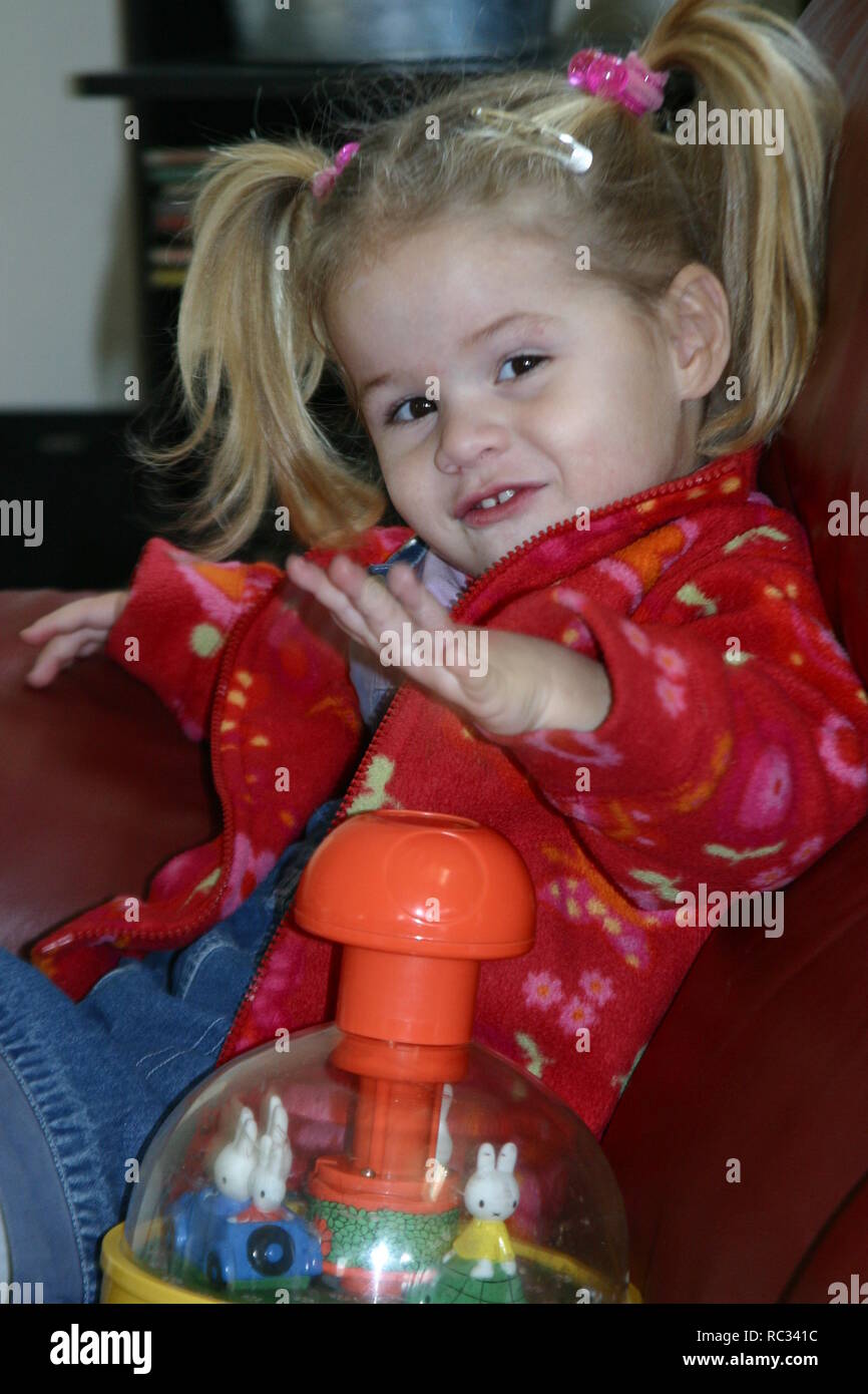 Little girl playing with humming top on sofa Stock Photo