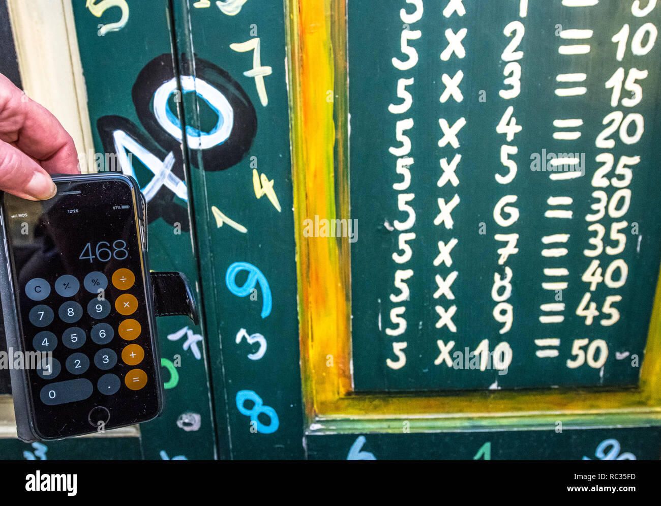 Iphone calculator at the side of the five times table painted onto a wooden door. Stock Photo