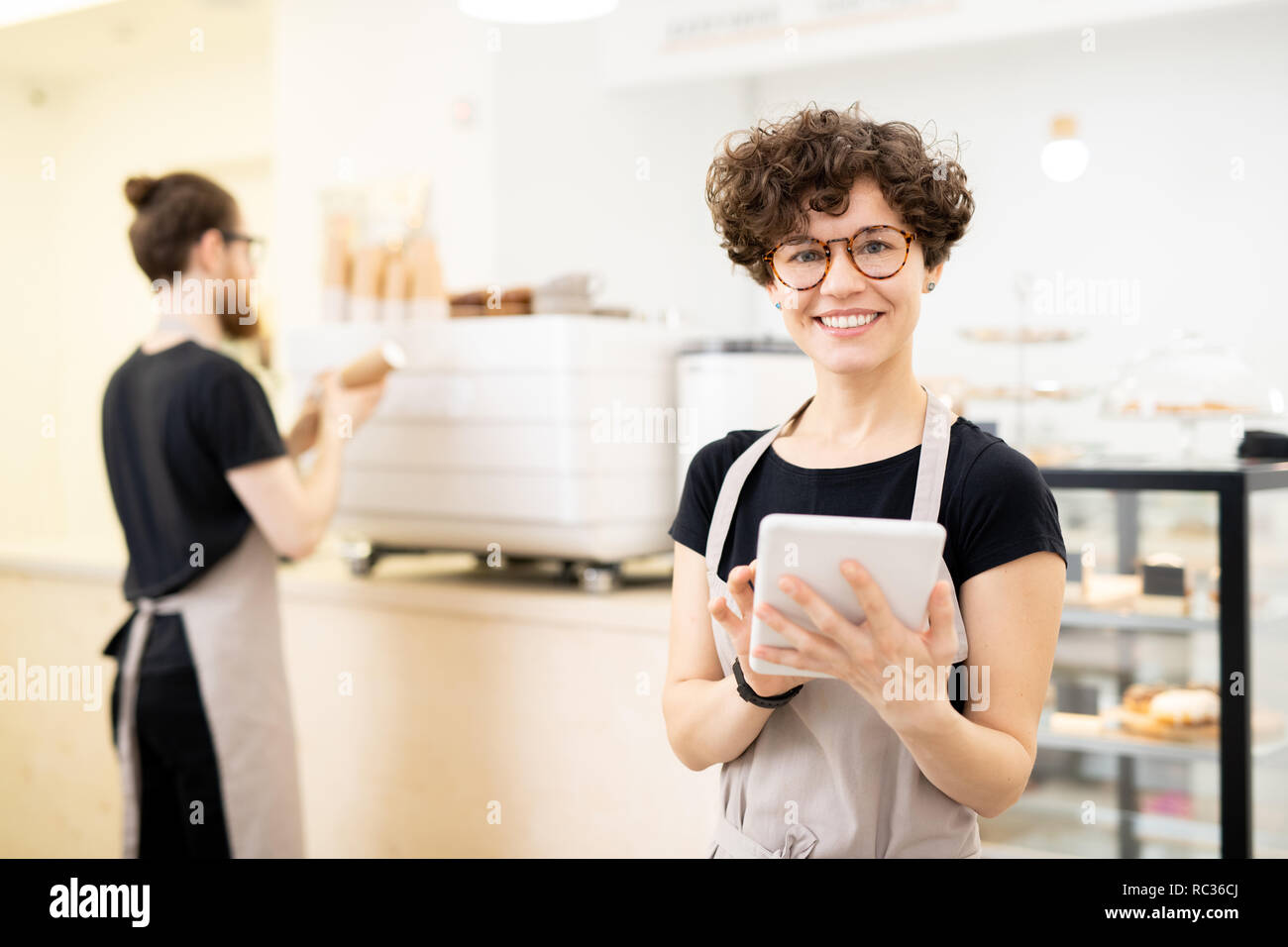 Smiling pretty waitress using tablet to take order Stock Photo