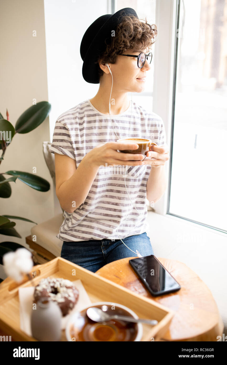 Pensive lady in hat drinking fresh-brewed coffee Stock Photo