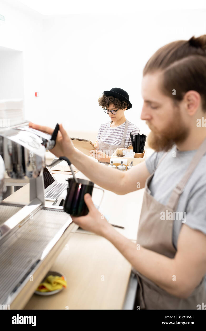Waitress writing down orders while barista making coffee Stock Photo