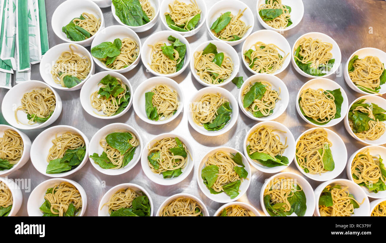 Preparation of some Thai or Chinese asian noodle soup with baby spinach - Asian noodles, bowls of noodles with packed Chinese sticks- top view Stock Photo