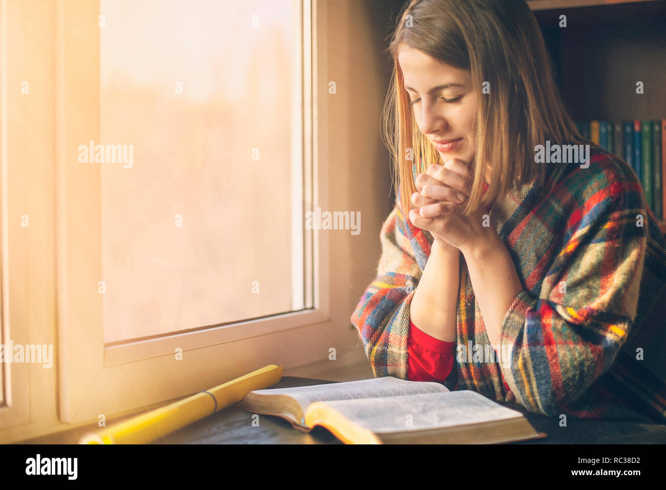 Beautiful woman praying having the Bible opened in front of he ...