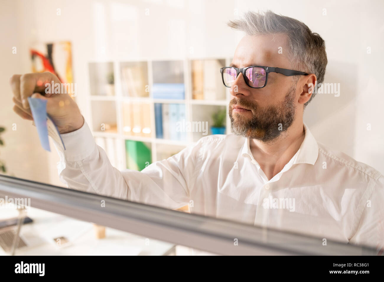 Serious manager making notes on glassy board Stock Photo - Alamy