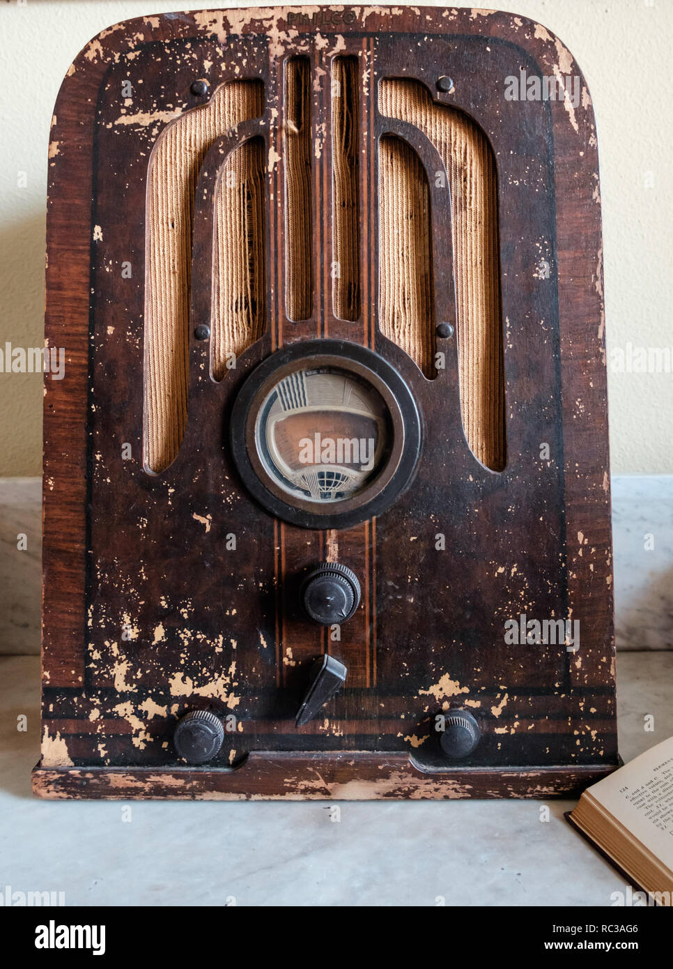 Antique Philco tombstone tube radio in wooden case model 37-620. Beat up vintage tabletop 1937 radio with part of open book in front. Stock Photo
