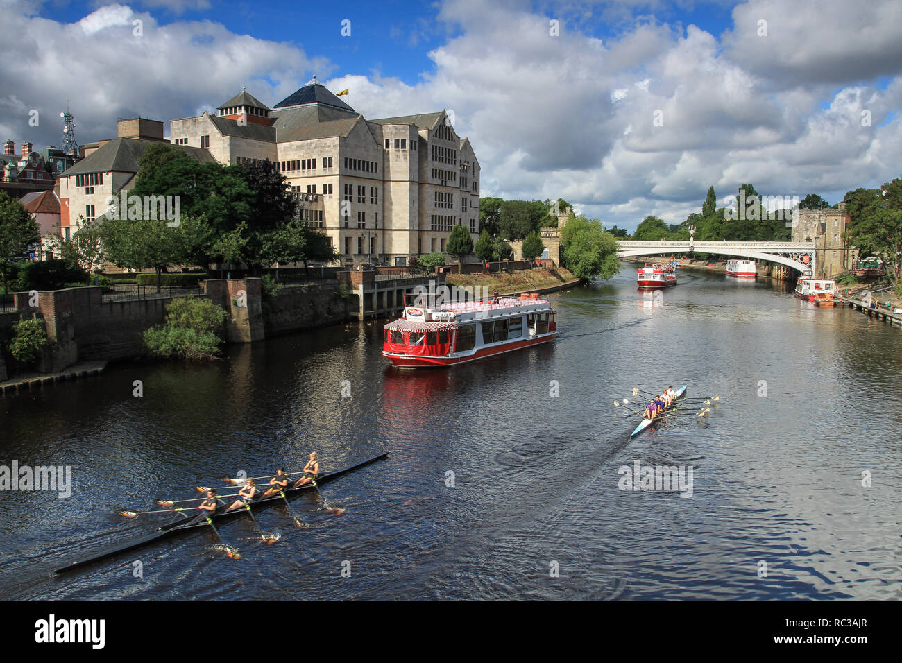 YORK, UK - SEPTEMBER 2, 2015.  A river cruise boat and rowing club boats sailing along the River Ouse in the centre of the historic City of York, UK Stock Photo