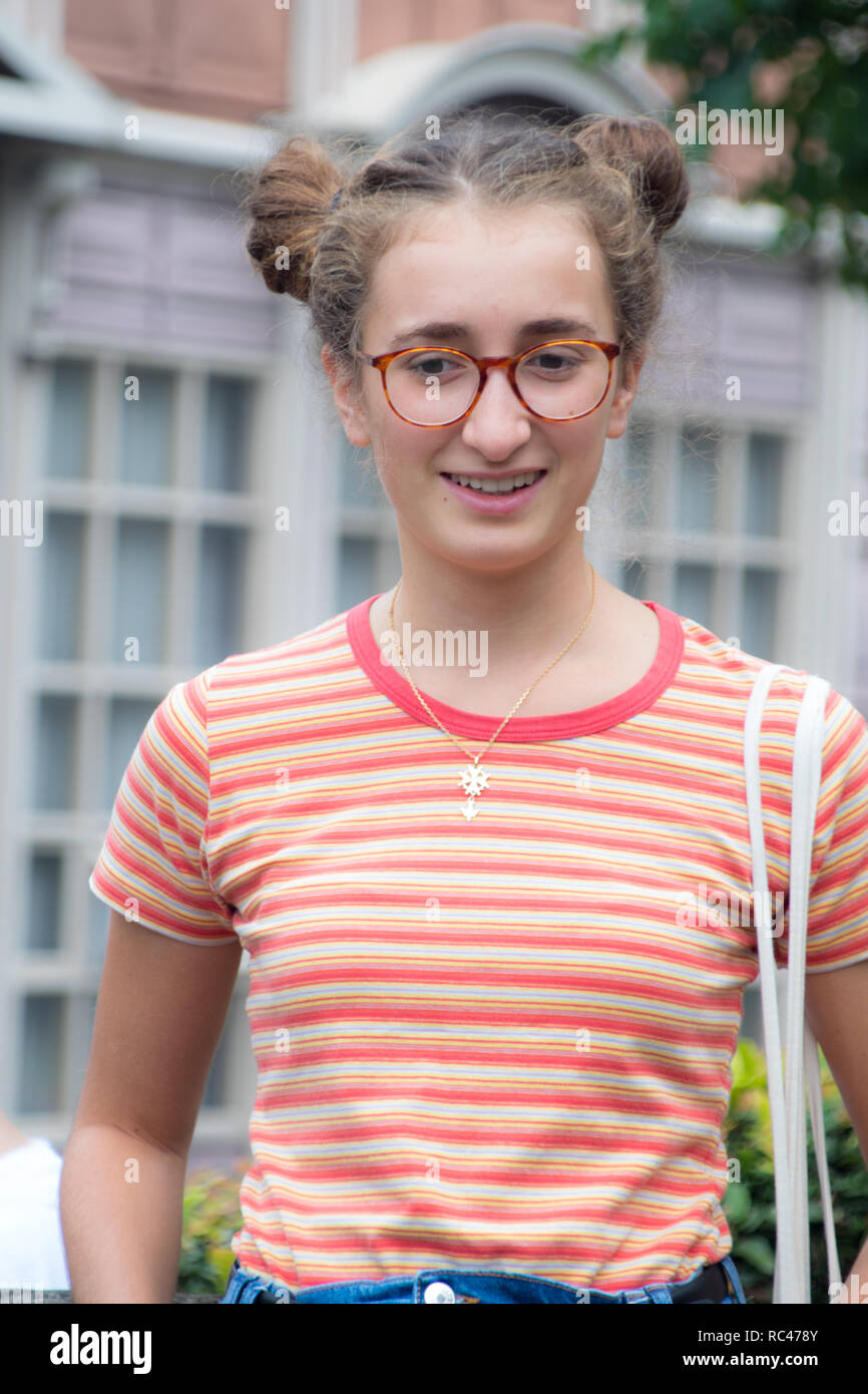 A portrait of a smiling geeky looking girl walking on a street Stock Photo