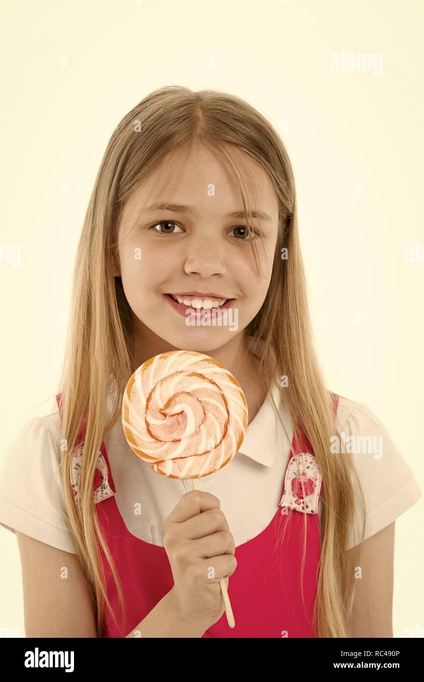 Girl smile with lollipop isolated on white. Small child smiling with candy on stick. Happy kid with swirl caramel. Food and dessert. Enjoying sweet lollipop. Diet and dieting. Stock Photo