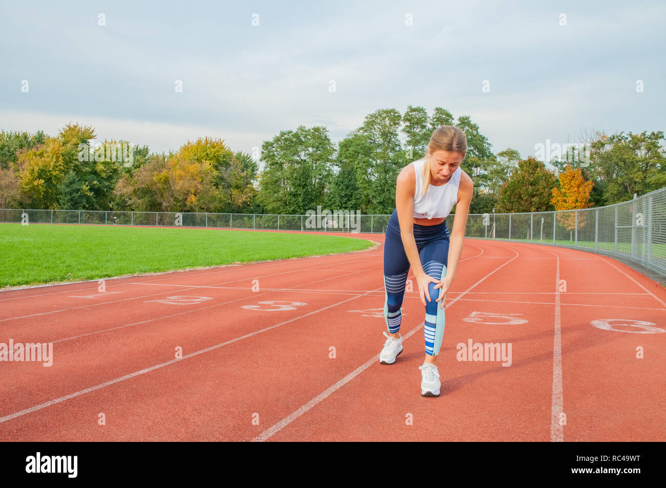 Sport knee injury. Woman has pain in knee after run outdoors at stadium