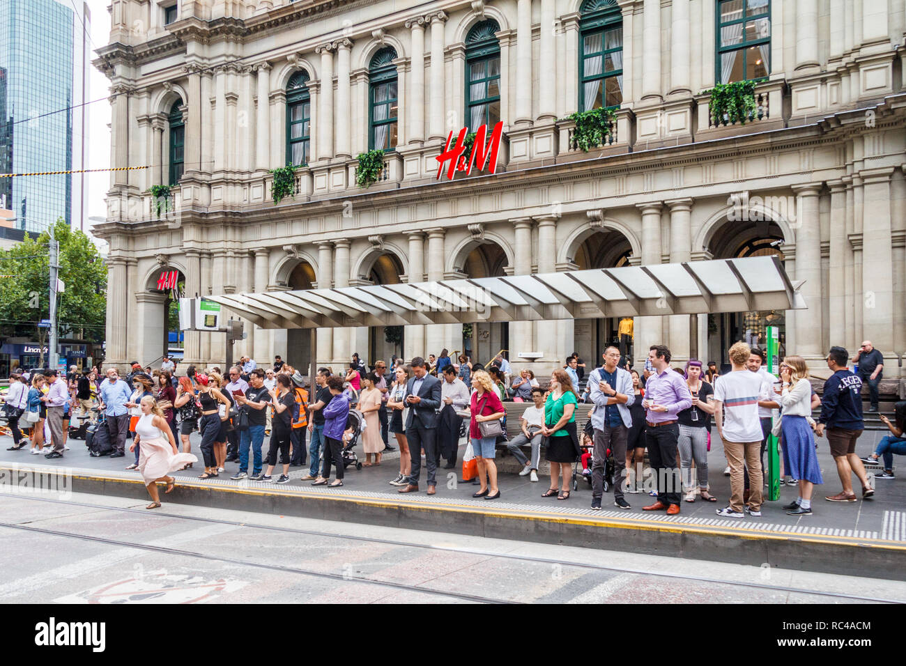 Melbourne, Australia - 21st February 2018: People waiting for the tram on Bourke Street outside the Old Post Office. The street is in the heart of the Stock Photo