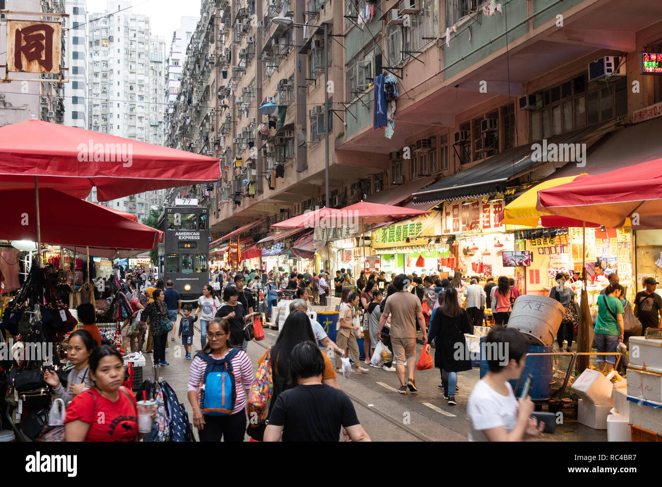 Hong Kong, China - October 13 2018: A large crowd walk in the Chun Yeung Street market in North Point in Hong Kong island with a tramway car going thr Stock Photo