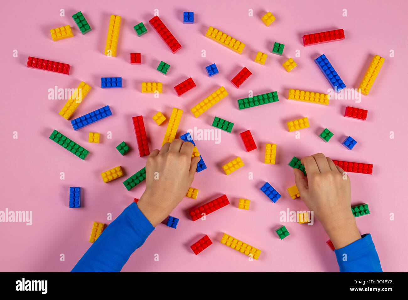 Kid hands playing with colorful building plastic bricks on pink ...
