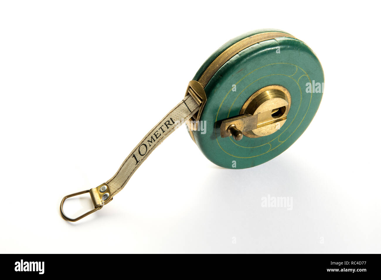 10 meter vintage measuring ribbon or tape-measure in round green body with yellow metal handle. Viewed from high angle in close-up, isolated on white  Stock Photo