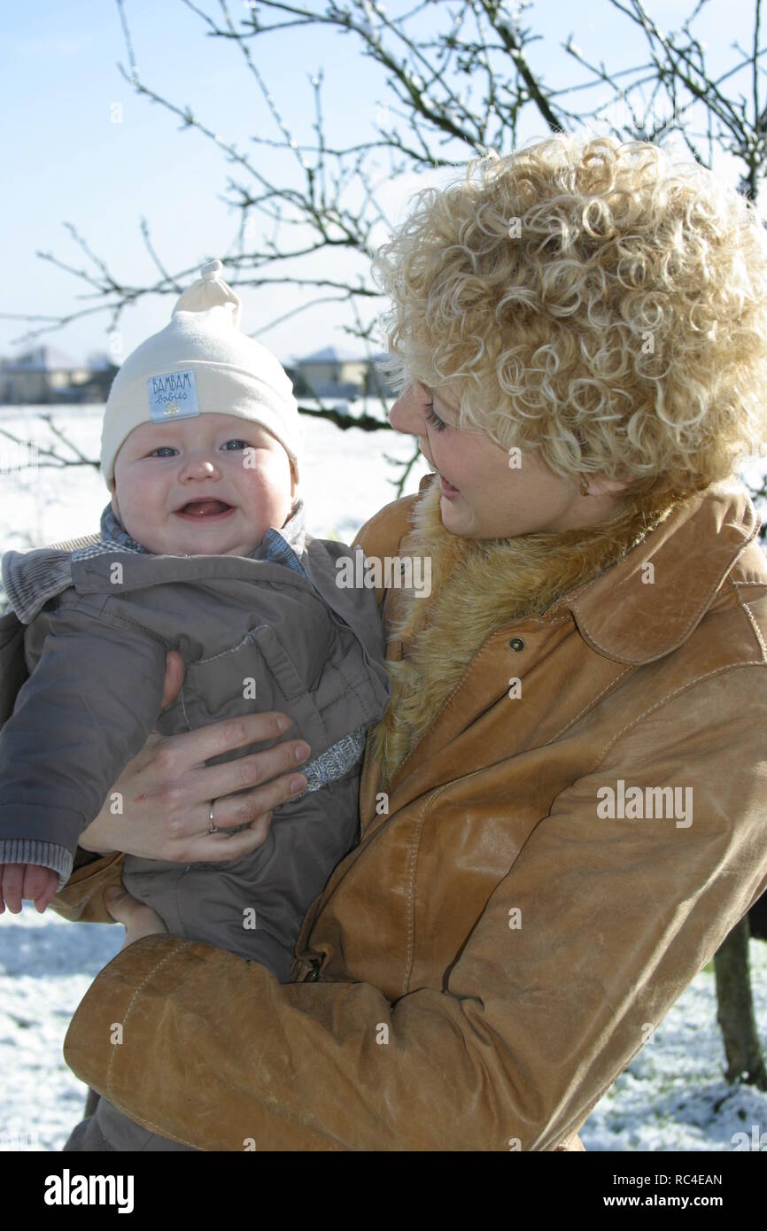 Happy mother and baby boy look at camera in winter outdoors Stock Photo