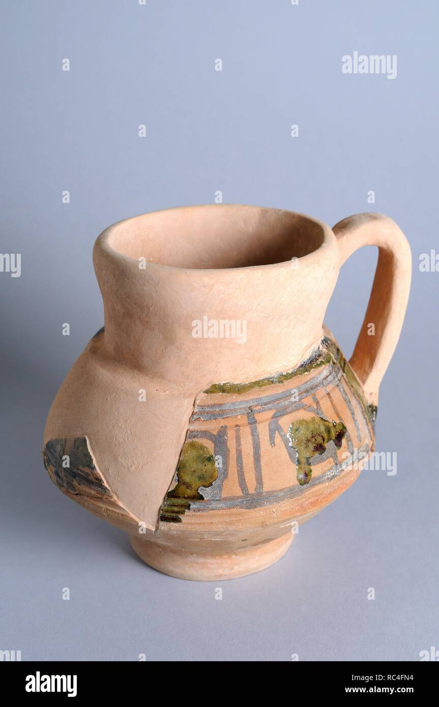 Ceramic jug with a handle and glaze decoration partial dry rope. Height 14 cm Diameter mouth 11 cm (12 th - 13 th CE) - Medieval period from the archaeological site of the 'Calle Seises ' in Alcalá de Henares - 'Burgo de Santiuste Museum ' (Madrid). SPAIN. Stock Photo