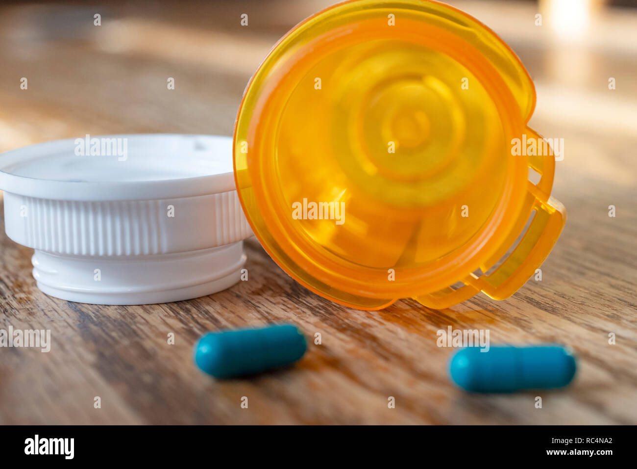 Close up of prescription pill bottle with the last two pills spilled out onto the kitchen table. Stock Photo